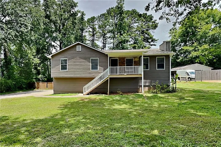 Ranch-style residence featuring a gray siding exterior and a front porch with white railings and stairs