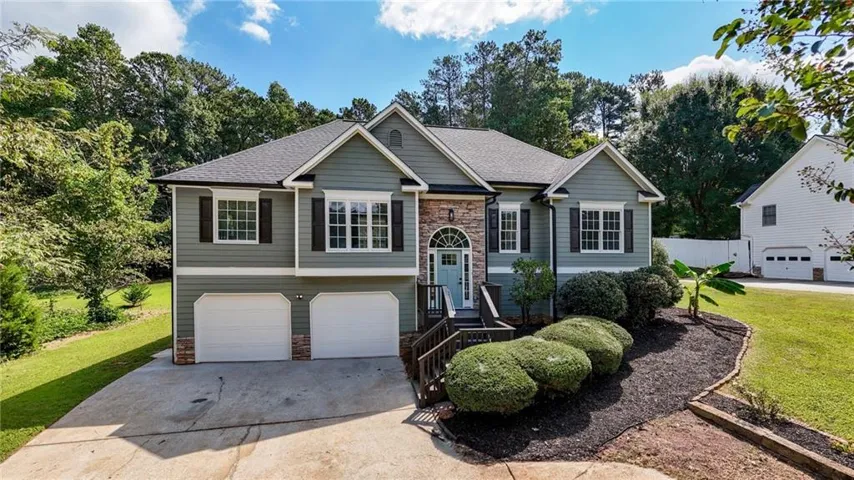 Two-story residence featuring composite shingle roofing, horizontal siding, stone accents, multiple windows with dark shutters, and an attached two-car garage