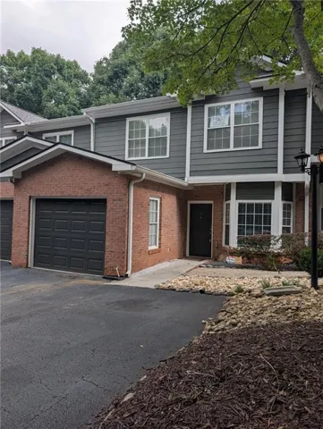 Brick and siding exterior with a dark garage door, bay window, and a paved driveway