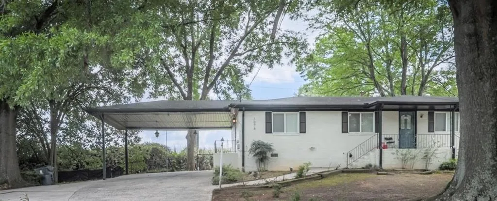 White painted brick exterior with black shutters and a covered carport