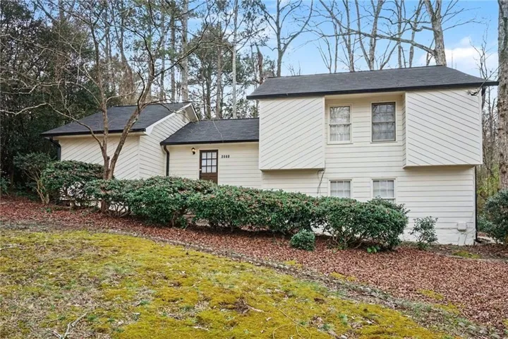 View of front of home with a front lawn and a shingled roof