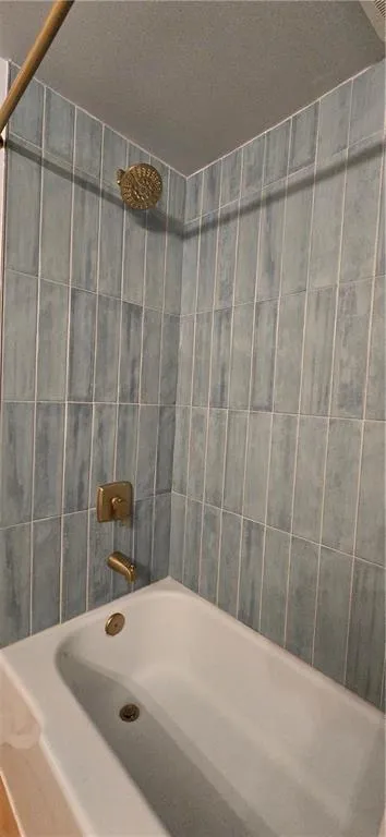 Bathroom featuring tiled shower / bath and a textured ceiling