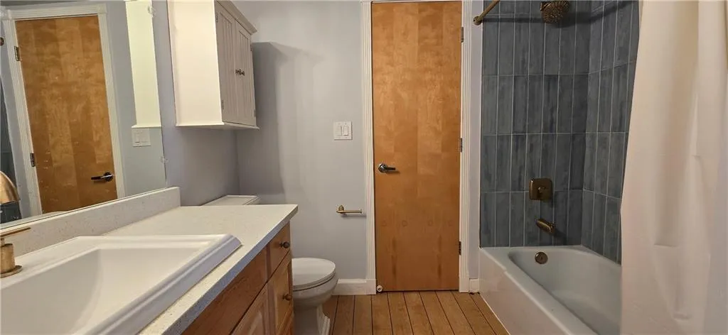 Full bathroom featuring vanity, toilet, wood-type flooring, and tiled shower / bath combo