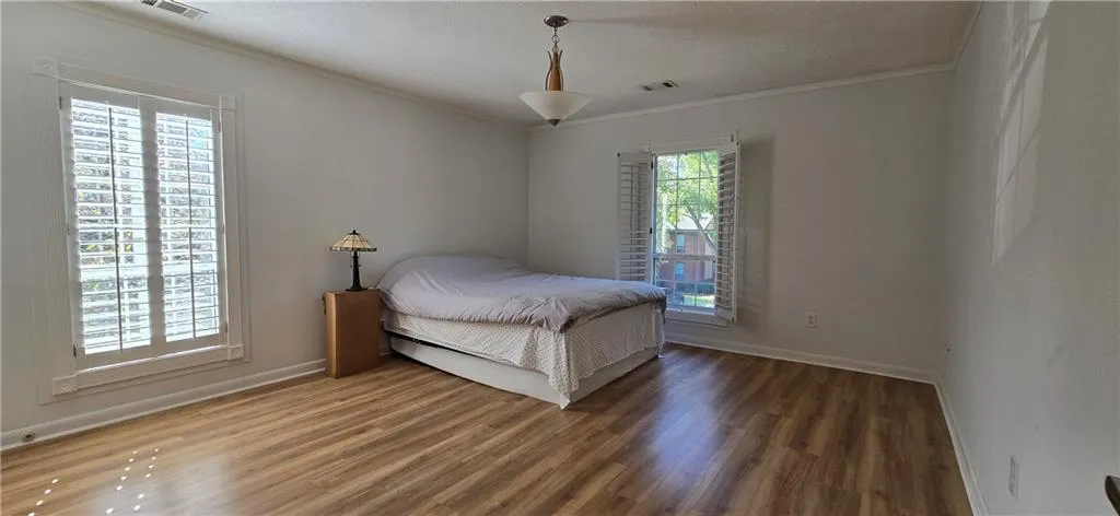 Bedroom featuring a textured ceiling, crown molding, and dark hardwood / wood-style flooring