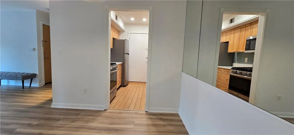 Kitchen with light brown cabinetry, appliances with stainless steel finishes, and light wood-type flooring
