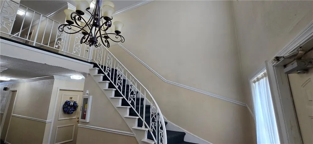 Staircase with a notable chandelier and ornamental molding