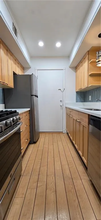Kitchen featuring pendant lighting, range, dishwasher, light brown cabinetry, and light hardwood / wood-style floors
