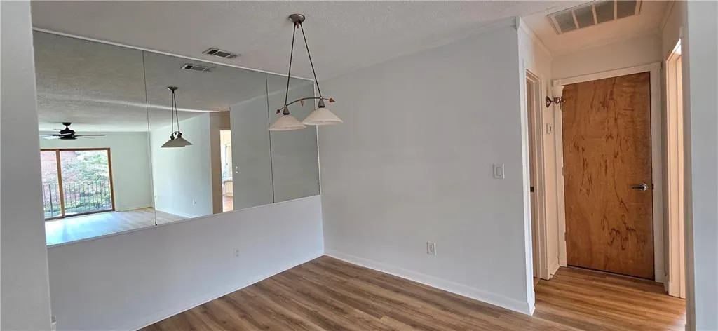 Empty room featuring wood-type flooring, a textured ceiling, ornamental molding, and ceiling fan