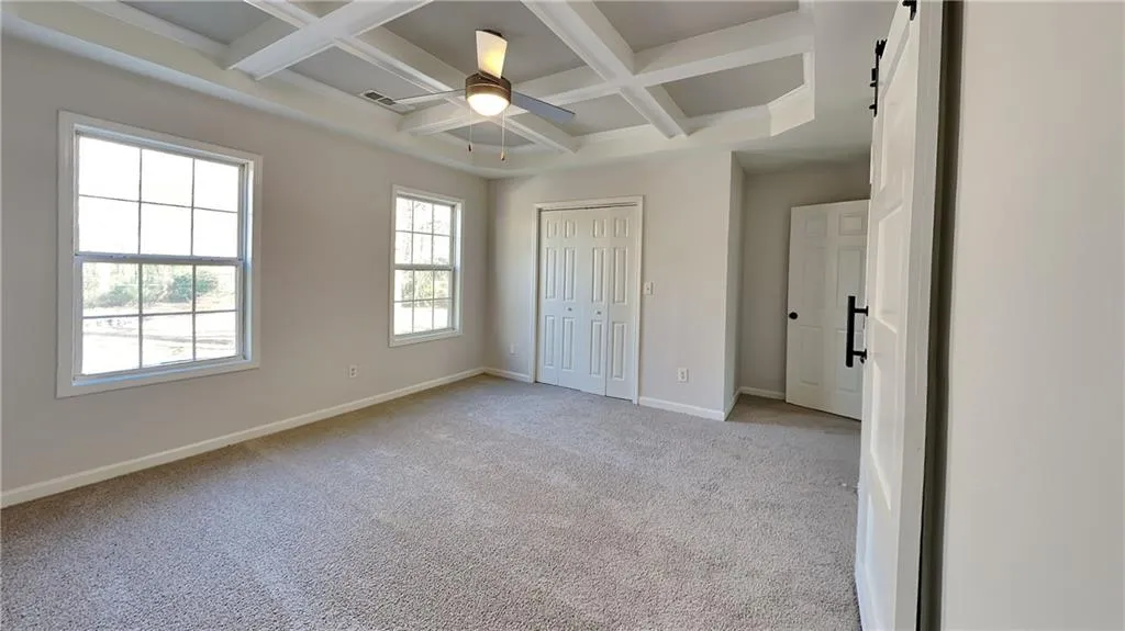 Unfurnished bedroom with a ceiling fan, baseboards, beamed ceiling, light carpet, and coffered ceiling