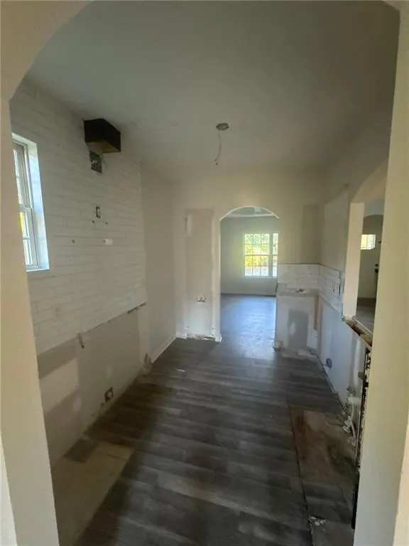 Unfurnished dining area with arched walkways and dark wood-style flooring