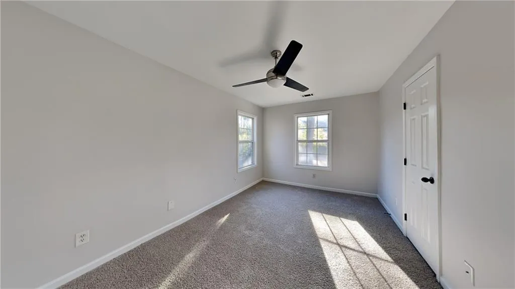 Unfurnished bedroom featuring baseboards, ceiling fan, carpet floors, and visible vents