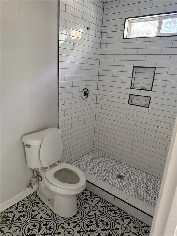 Full bath with a stall shower, tile patterned flooring, and a baseboard radiator