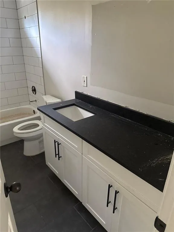 Bathroom with vanity, dark tile patterned flooring, and bathtub / shower combination