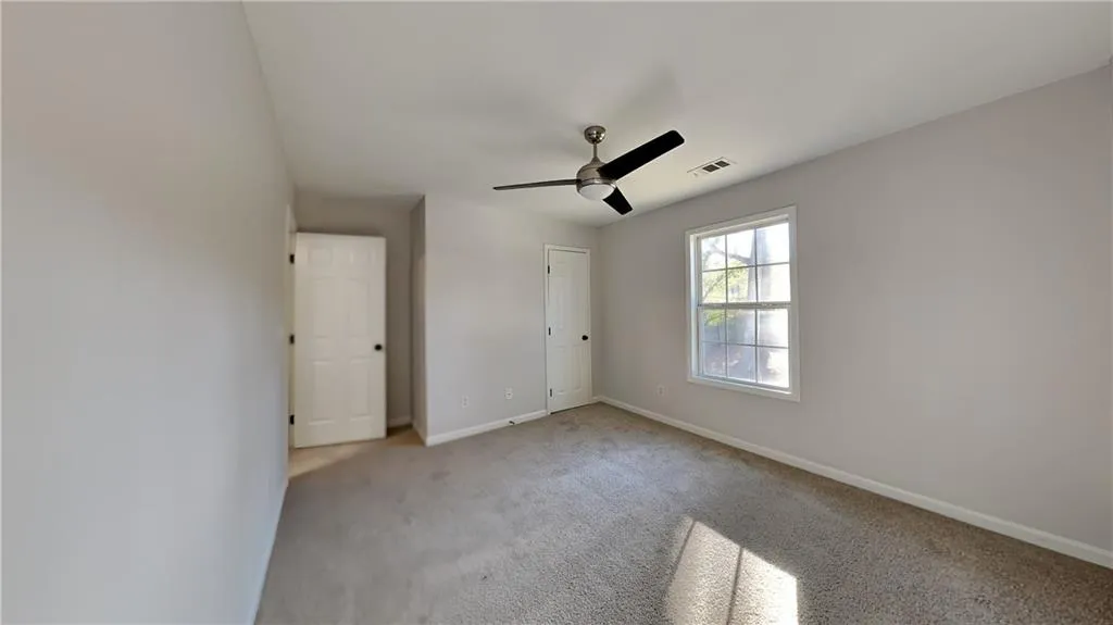 Unfurnished bedroom featuring visible vents, baseboards, ceiling fan, and light carpet
