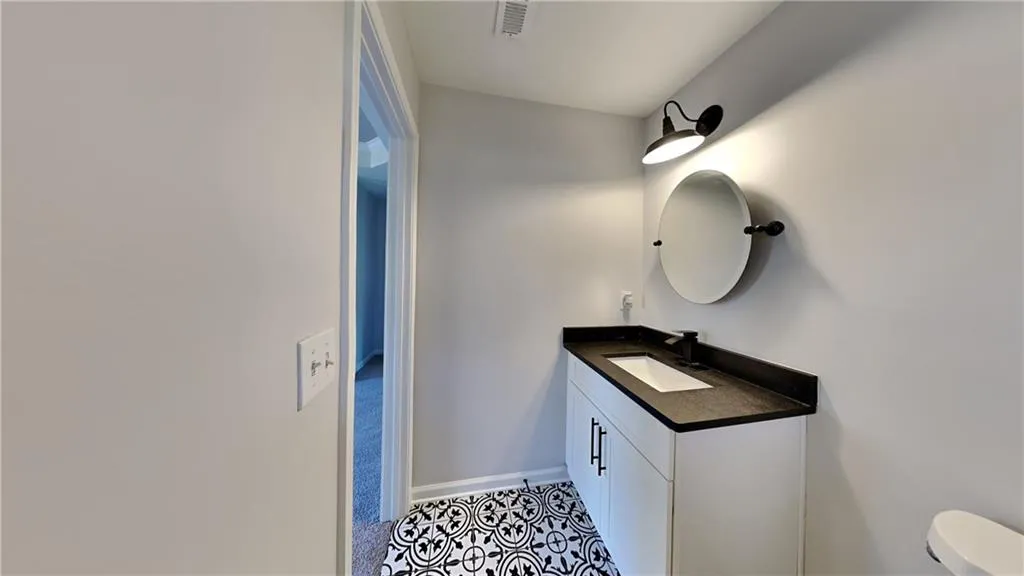 Bathroom with vanity, baseboards, toilet, and visible vents