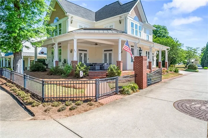 Grand two-story residence featuring a wraparound covered porch with white columns and a dark metal roof