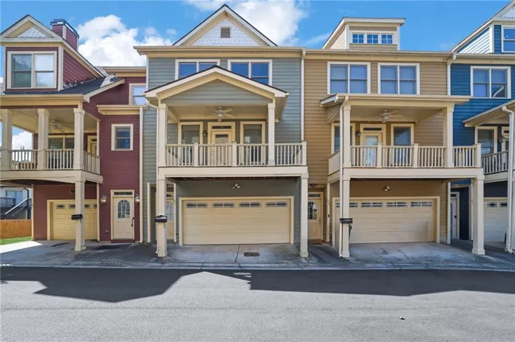 Multi-level townhome featuring a front-facing balcony, an attached garage, and a transom window above the entry door