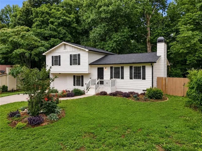 Split-level residence featuring white siding and dark shutters