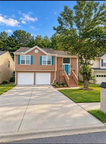 Split-level residence featuring a two-car garage, concrete driveway, and a welcoming front entrance with wood stairs