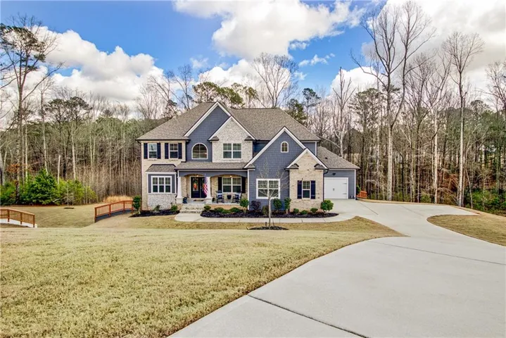 Stone and siding exterior with a covered porch, attached two-car garage, and a concrete driveway