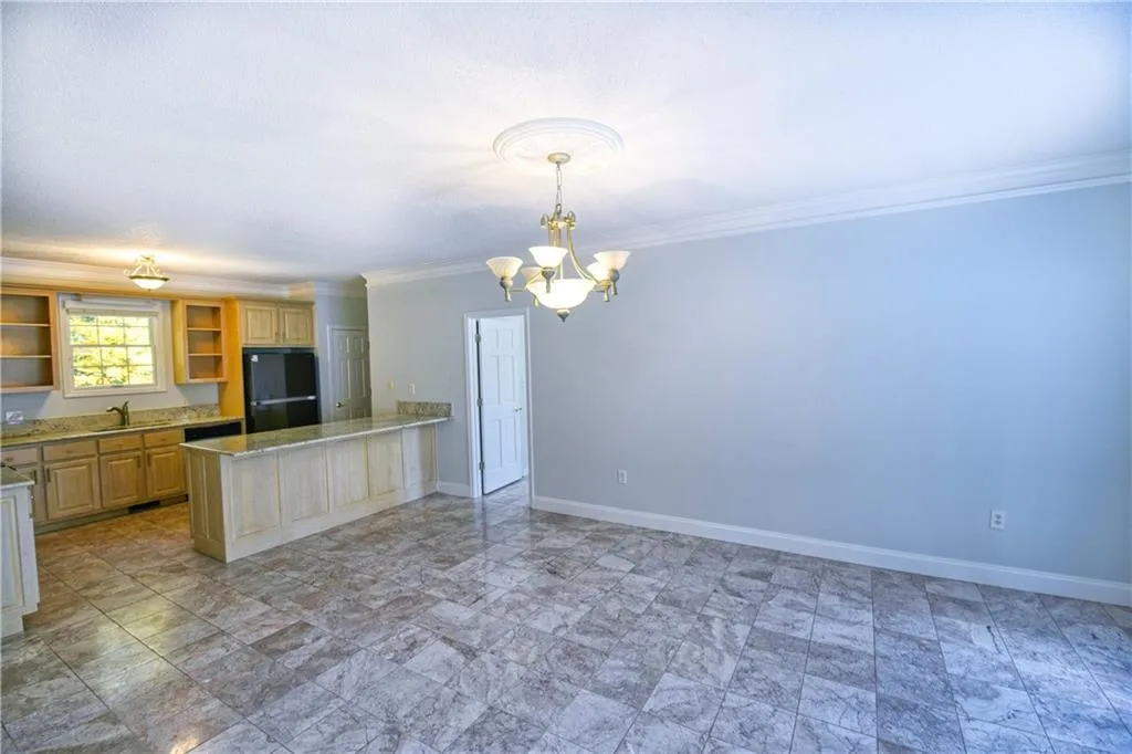 Kitchen featuring baseboards, open shelves, a chandelier, and freestanding refrigerator