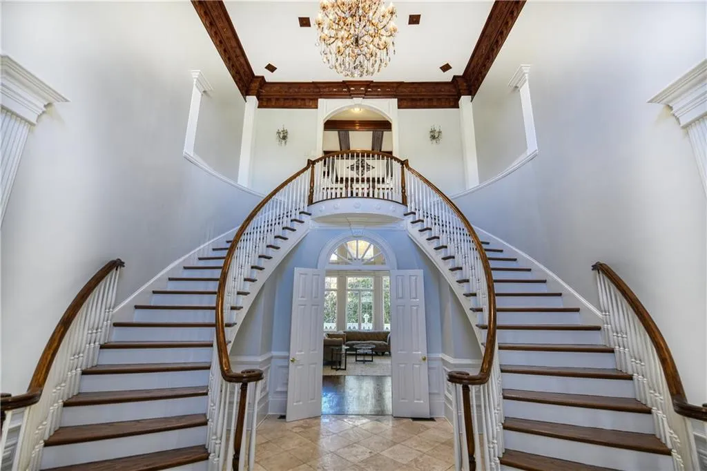 Stairs featuring a towering ceiling, arched walkways, crown molding, and a chandelier