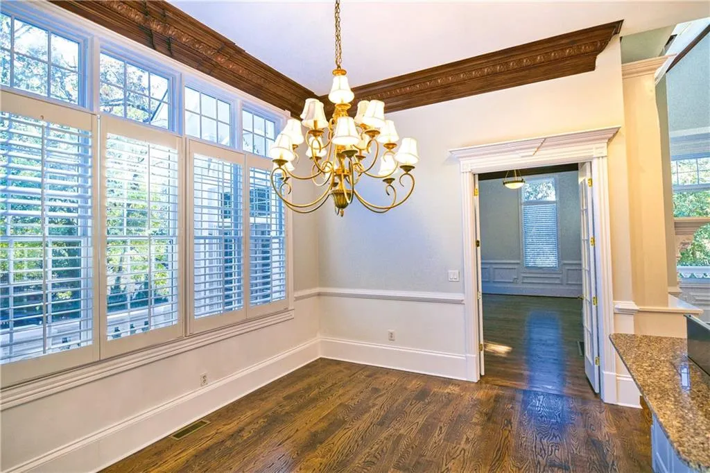 Unfurnished dining area featuring visible vents, a chandelier, crown molding, dark wood-type flooring, and a wealth of natural light