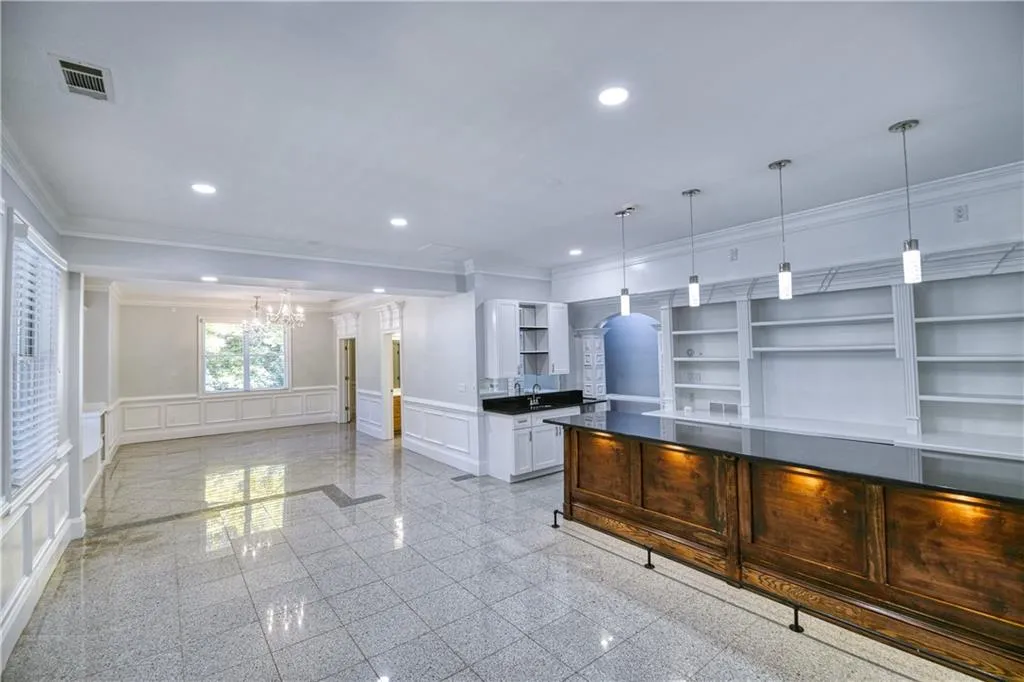 Kitchen featuring a wainscoted wall, open shelves, granite finish floor, a decorative wall, and recessed lighting