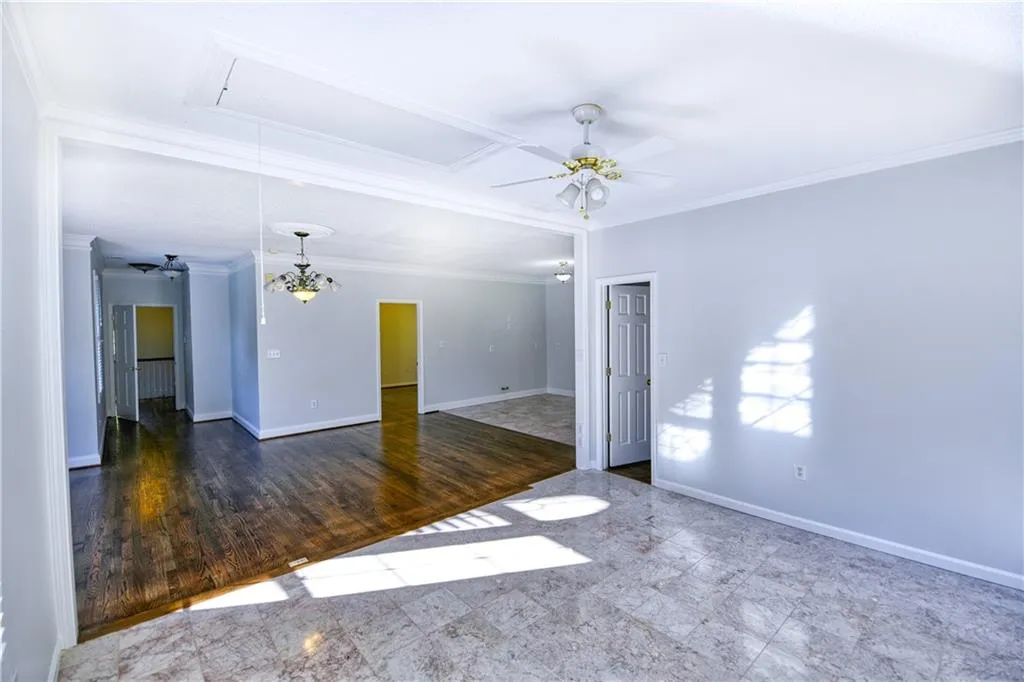 Spare room with attic access, baseboards, crown molding, and ceiling fan