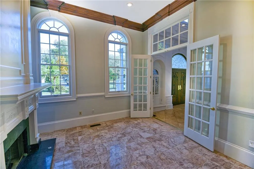 Entrance foyer with french doors, ornamental molding, a fireplace with flush hearth, and baseboards