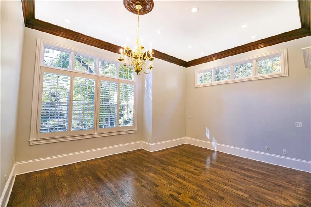 Unfurnished room featuring baseboards, crown molding, a healthy amount of sunlight, and a notable chandelier