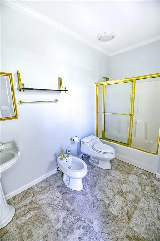 Full bathroom with toilet, ornamental molding, baseboards, bath / shower combo with glass door, and a bidet