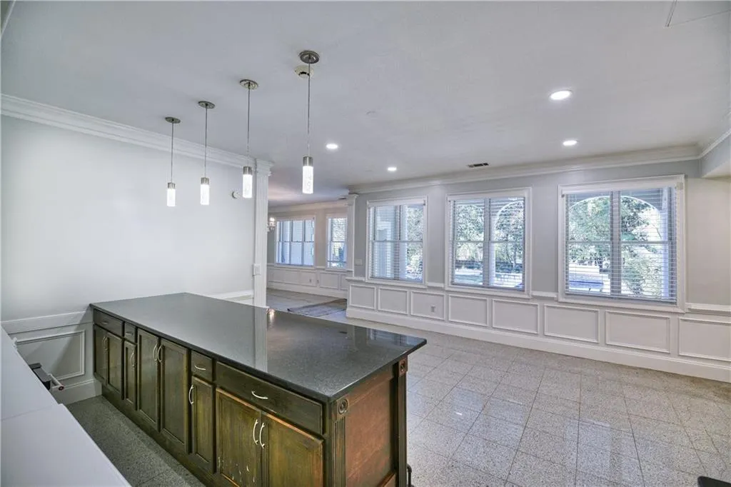 Kitchen with recessed lighting, ornamental molding, granite finish floor, a decorative wall, and wainscoting