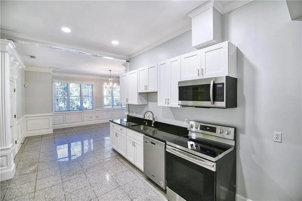 Kitchen with crown molding, stainless steel appliances, a wainscoted wall, a sink, and a decorative wall