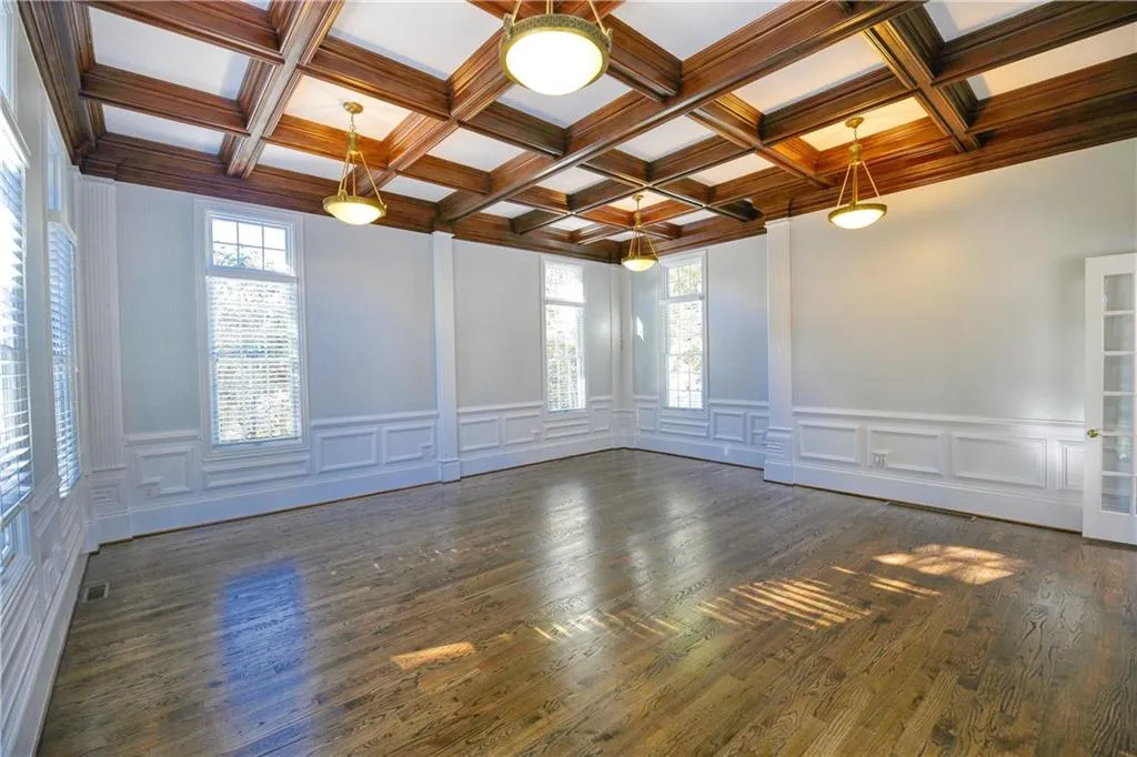 Empty room featuring coffered ceiling, beamed ceiling, visible vents, and dark wood-style flooring