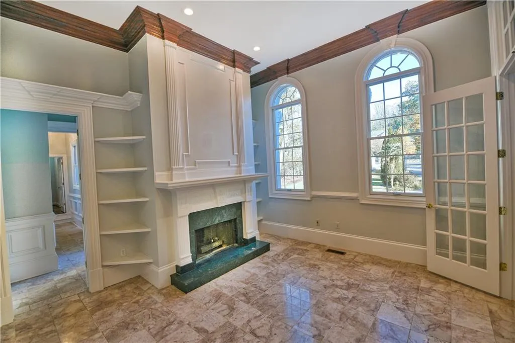 Unfurnished living room featuring a high end fireplace, ornamental molding, built in features, and visible vents