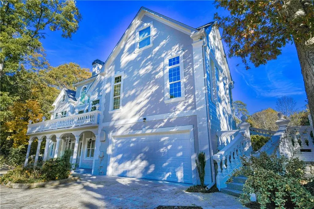 View of front of property with a chimney, a balcony, concrete driveway, and an attached garage
