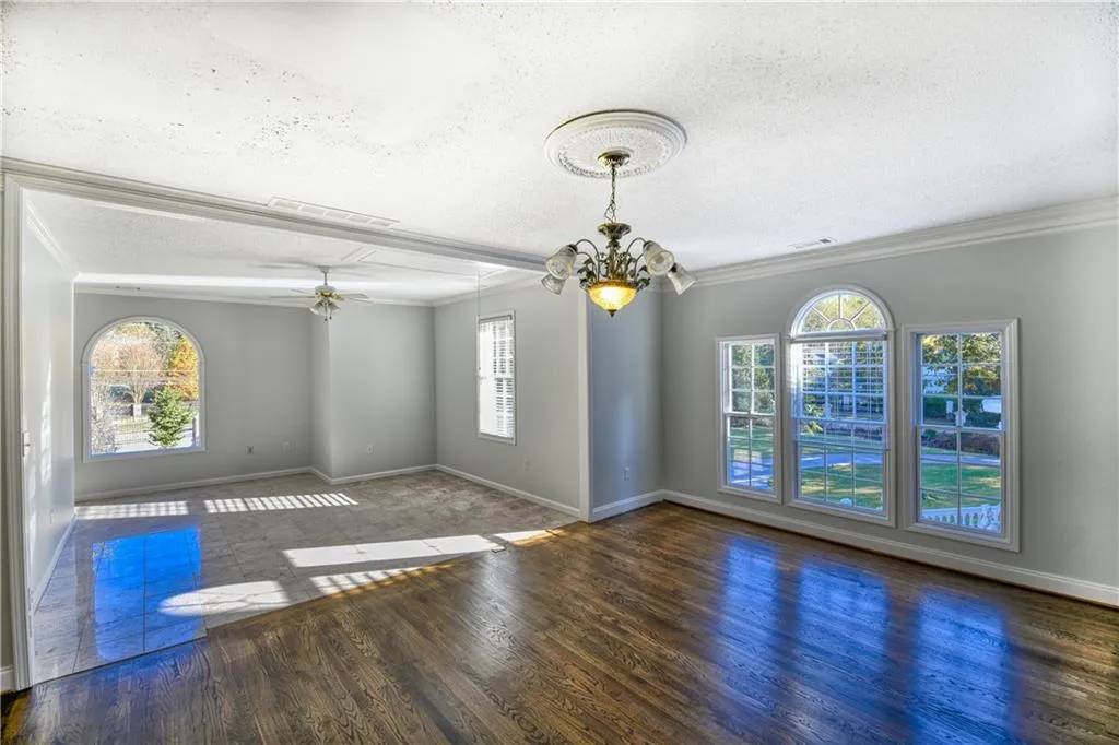 Unfurnished room with wood finished floors, ornamental molding, and visible vents