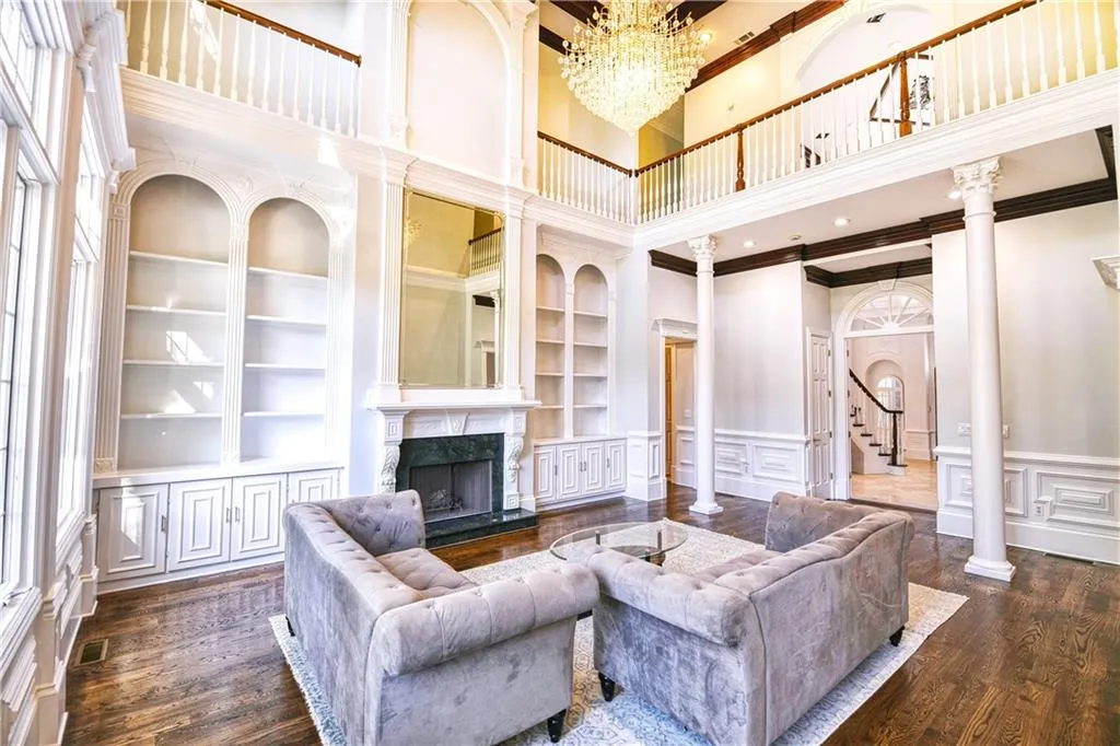 Living room featuring crown molding, a premium fireplace, built in shelves, a decorative wall, and wood finished floors