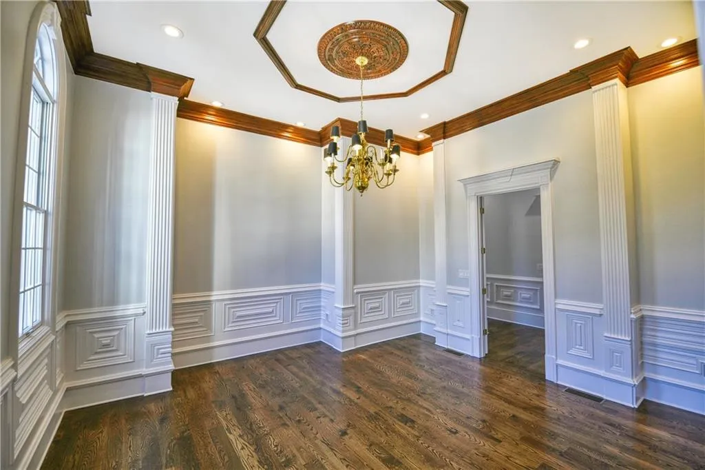 Unfurnished dining area with a notable chandelier, wood finished floors, wainscoting, visible vents, and recessed lighting