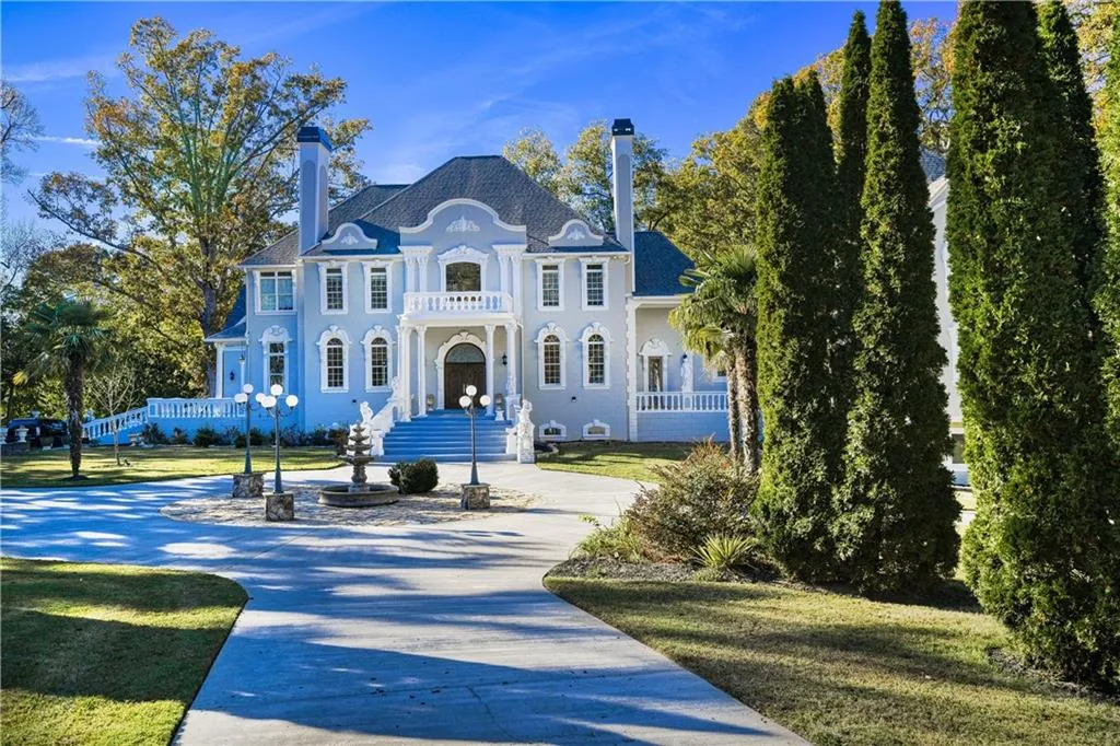 View of front of property with a balcony, a chimney, concrete driveway, and a front yard