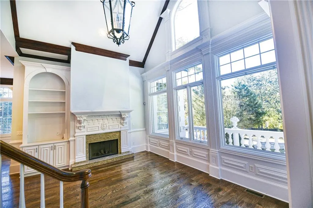 Unfurnished living room featuring a fireplace with raised hearth, dark wood-style floors, built in features, visible vents, and ornamental molding