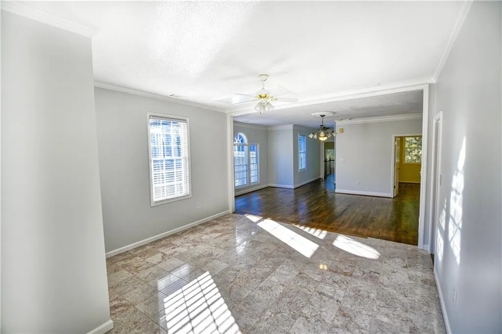 Unfurnished room featuring baseboards, ceiling fan with notable chandelier, and ornamental molding