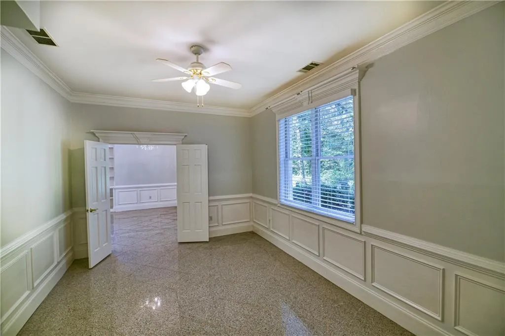 Spare room featuring granite finish floor, visible vents, ceiling fan, and a decorative wall