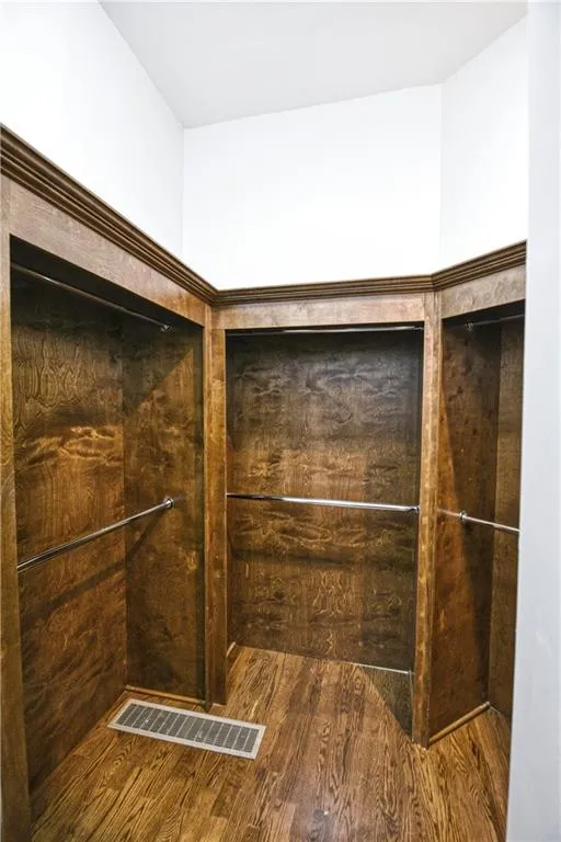 Walk in closet featuring visible vents and wood finished floors