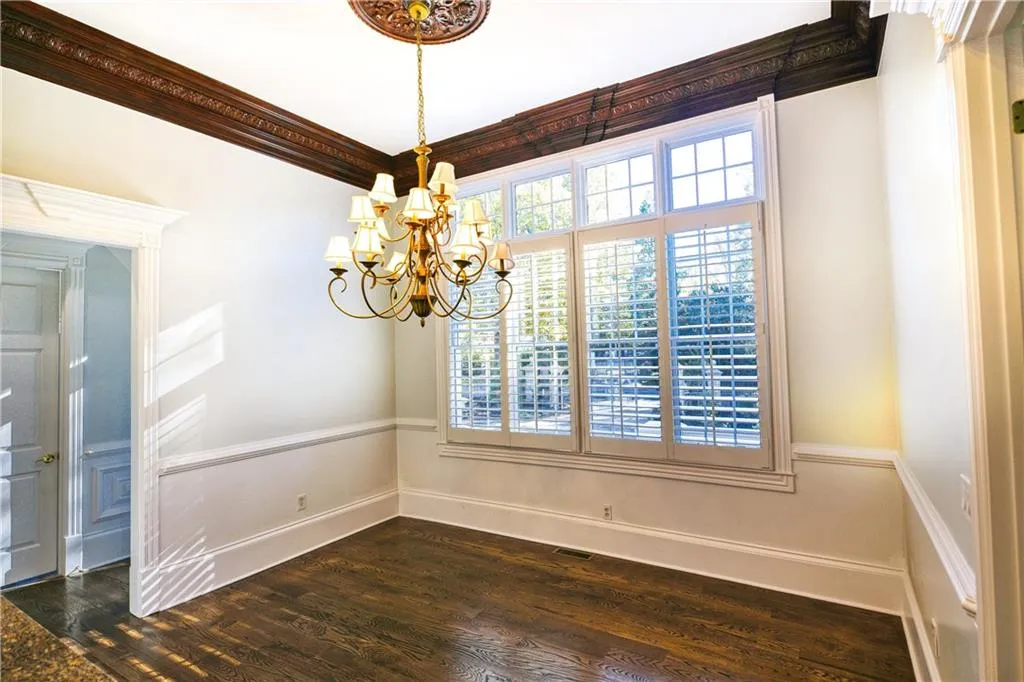 Empty room with dark wood-style floors, crown molding, a chandelier, and a wealth of natural light
