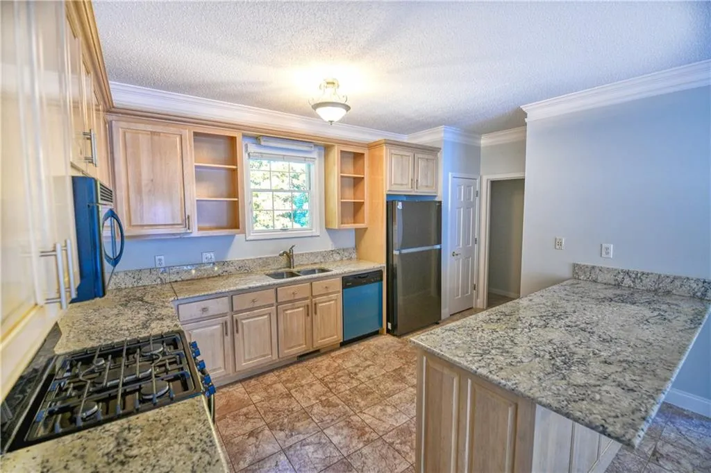 Kitchen with open shelves, freestanding refrigerator, dishwashing machine, a peninsula, and light brown cabinets