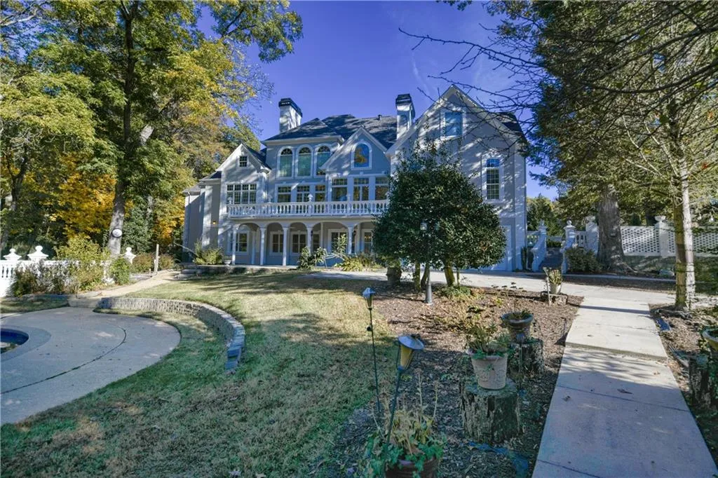 Rear view of property with a balcony, a chimney, fence, and a yard