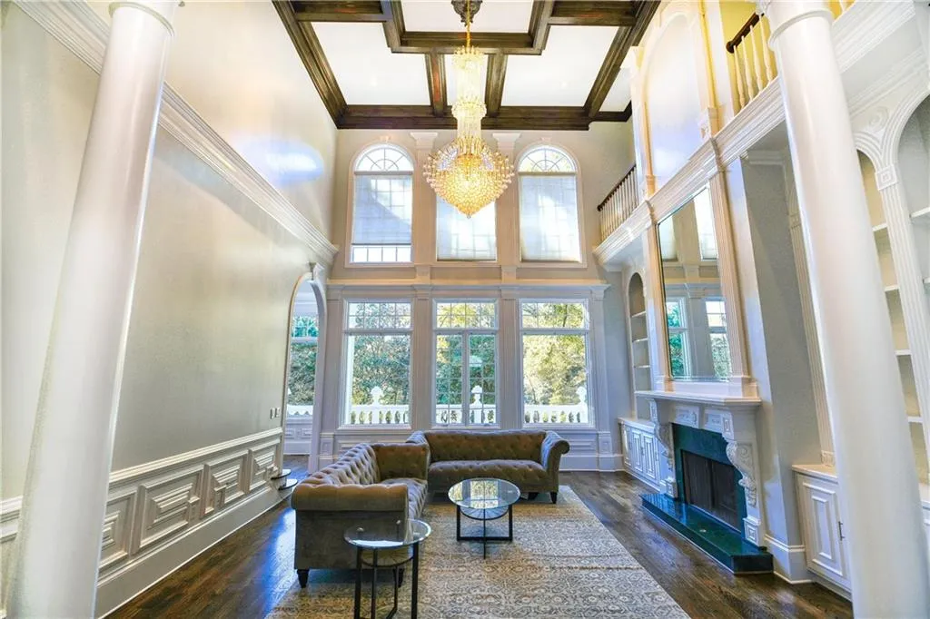 Living room with a fireplace, wood finished floors, coffered ceiling, and a notable chandelier