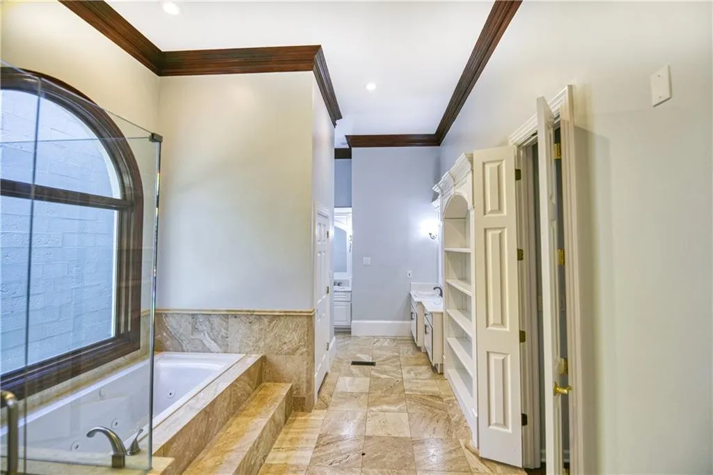Bathroom with baseboards, ornamental molding, recessed lighting, vanity, and a whirlpool tub